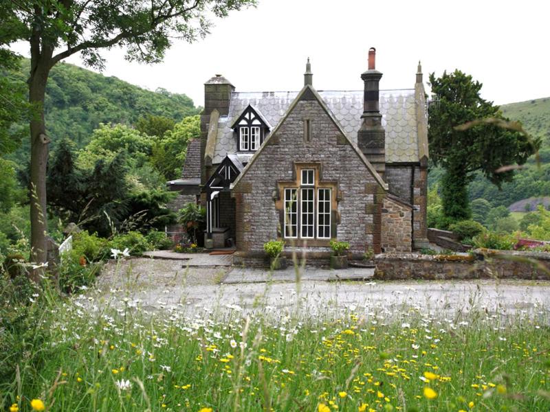 een oud stenen huis met een bloemenveld bij The Lodge in Cressbrook