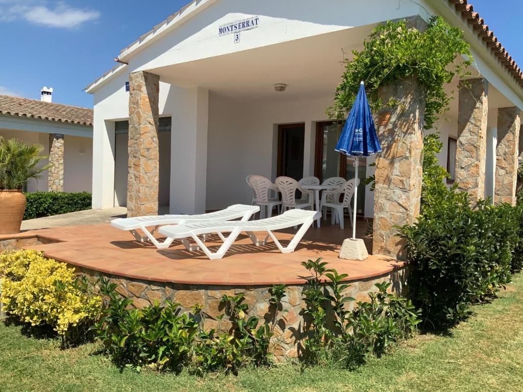 un patio con 2 sillas y una sombrilla azul en Villa Montserrat 3, Terrace & Pool, en Sant Martí d’Empúries