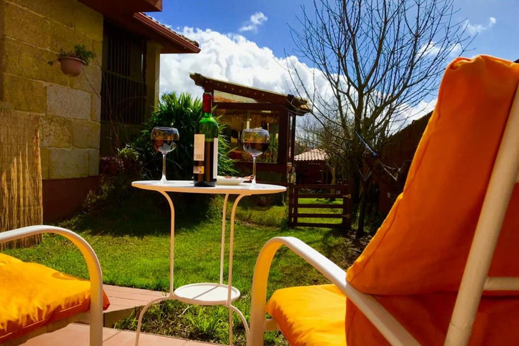 a chair and a table with two glasses of wine at Tranquila casita de invitados en Vigo con chimenea in Vigo