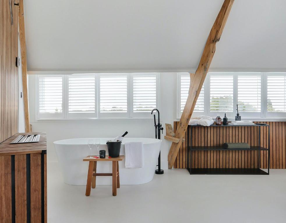 Dieses weiße Zimmer verfügt über eine Badewanne und einen Tisch. in der Unterkunft Boutique hotel Hippe Hendrik in Hendrik-Ido-Ambacht