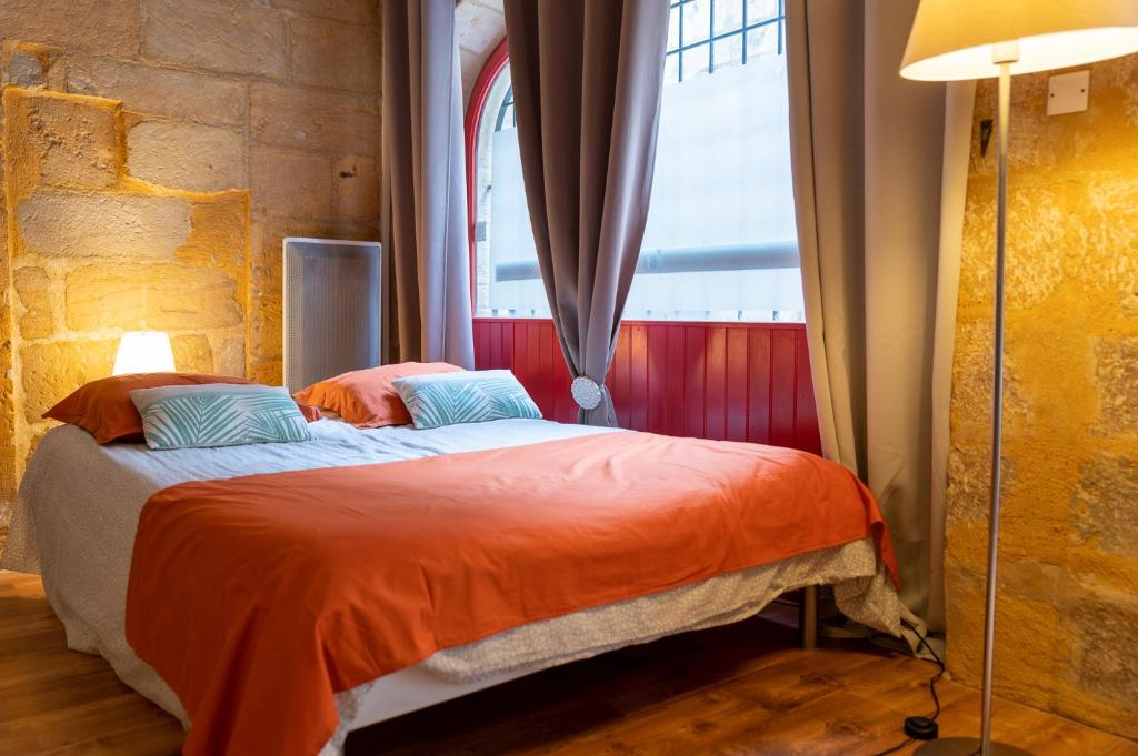 ペリグーにあるLe Logis du puy ST FRONT gite urbain PÉRIGUEUXのベッドルーム1室(オレンジのシーツが入ったベッド1台、窓付)