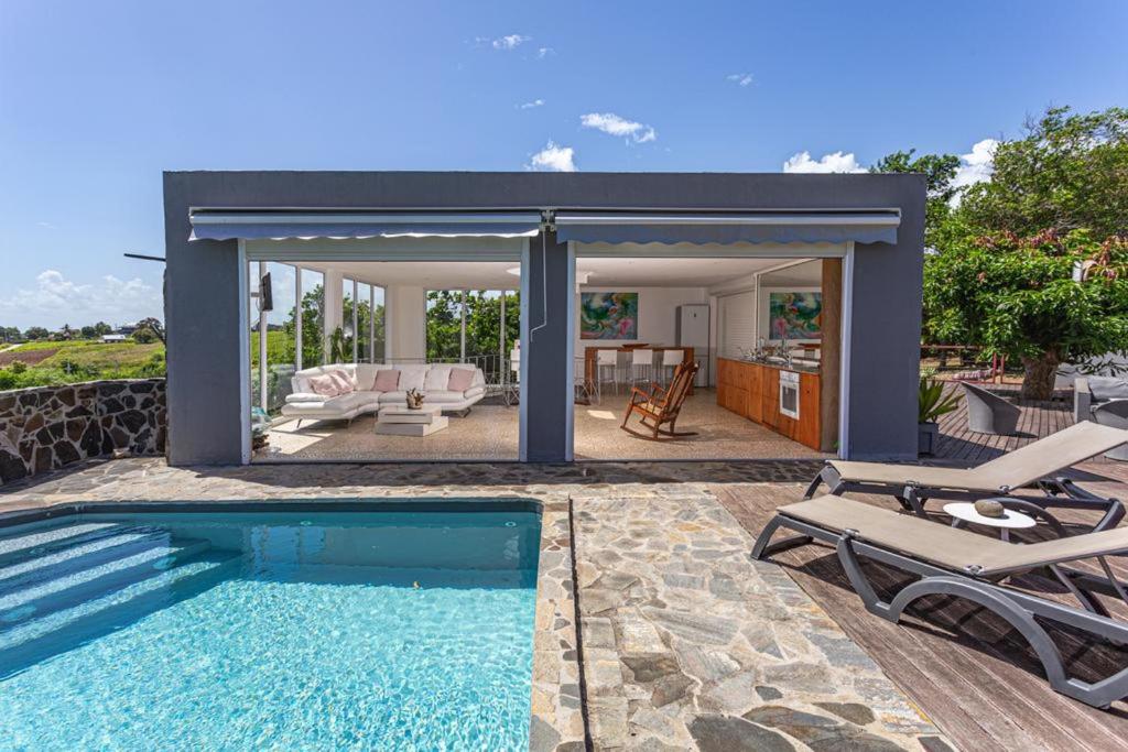 una piscina con patio y una casa en Villa élégante à Sainte-Rose avec piscine privée, en Sainte-Rose