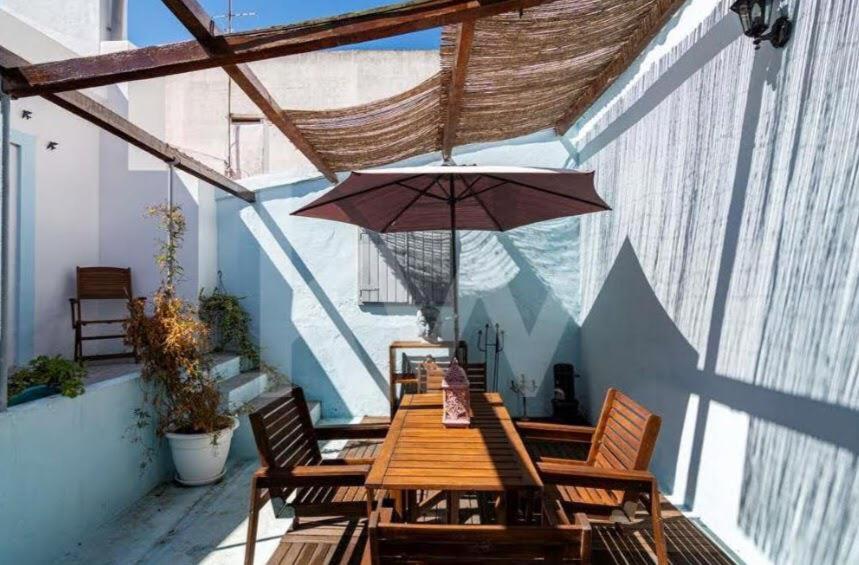 una mesa de madera con sillas y una sombrilla en el balcón en Blue Vintage House, en Setúbal