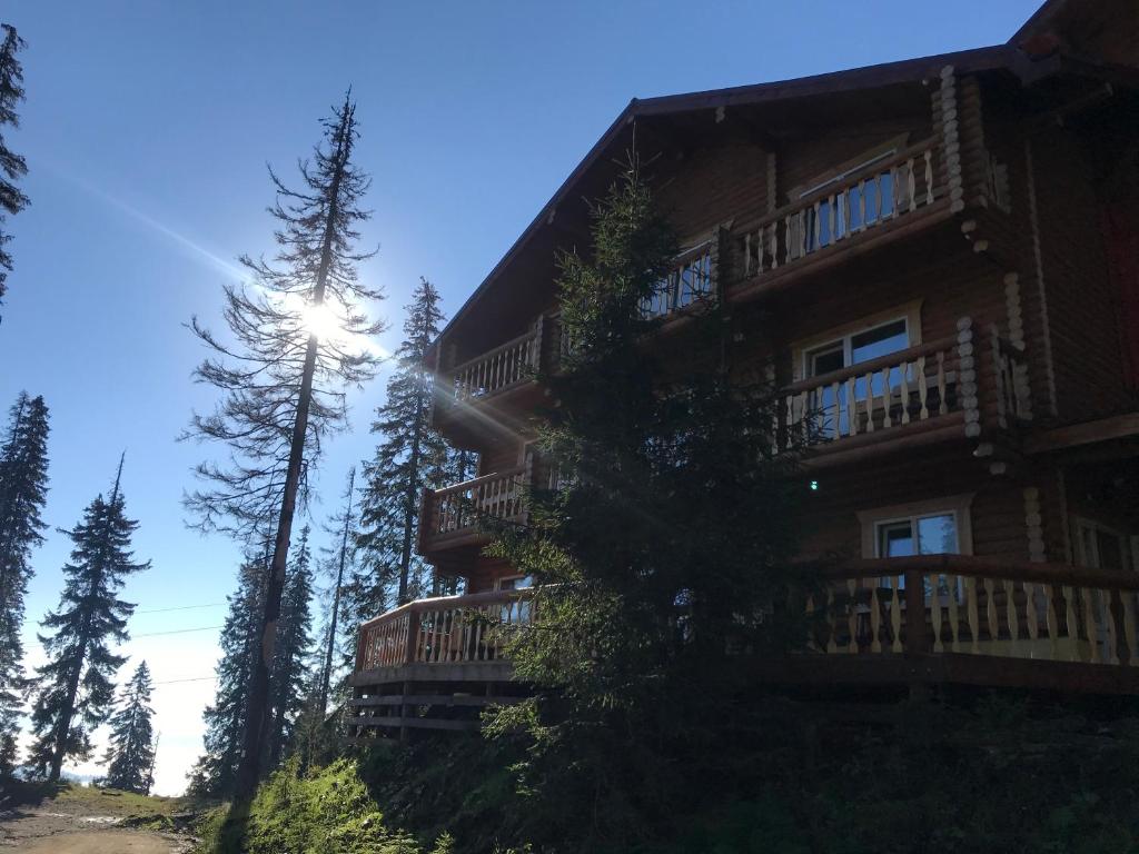 a building on a hill with the sun in the background at Alpin Eco Chalet & Wellness in Dragobrat
