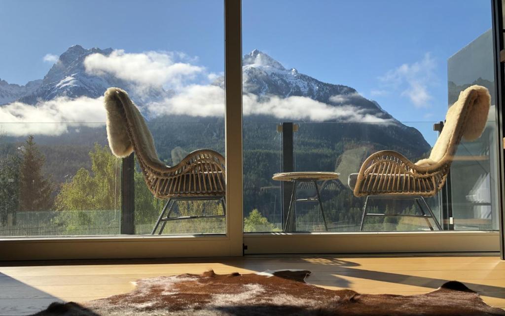 a room with two chairs and a view of a mountain at Chasa Rachögna in Scuol