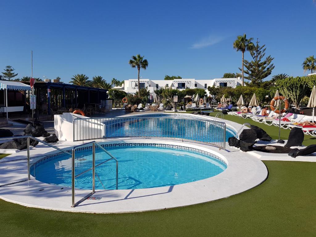 a swimming pool at a resort with people sitting around it at Avenue Puerto del Carmen in Puerto del Carmen