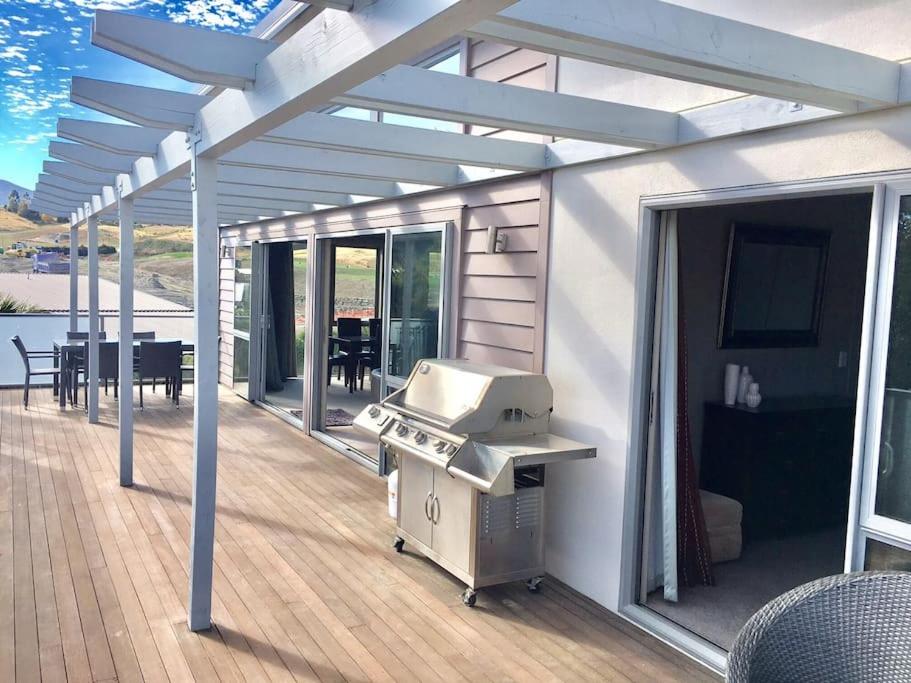 a barbecue grill on a deck with a table at Stunning Bob Lee Place in Wanaka