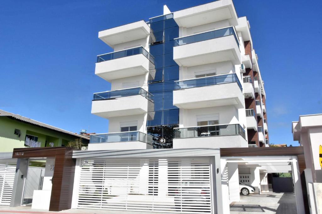 a white building with balconies on the side of it at Residencial Santinho Beach in Florianópolis