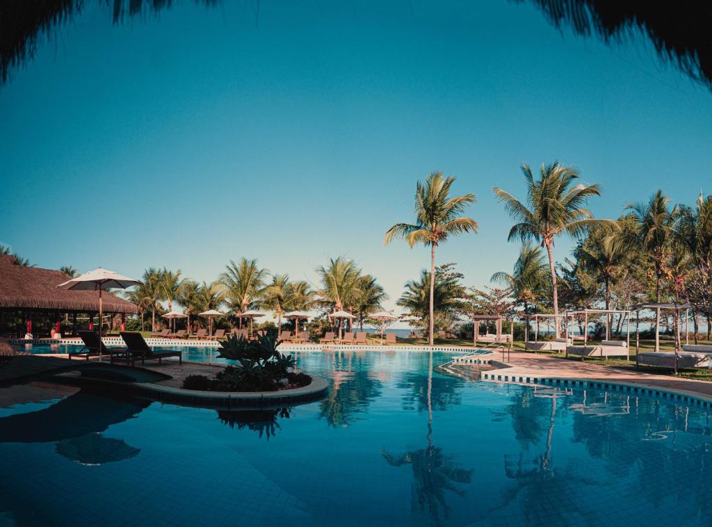 une grande piscine bordée de palmiers et de chaises dans l'établissement Vila Angatu Eco Resort SPA, à Santo André