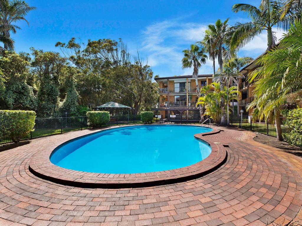 a swimming pool in a brick walkway around a house at Pelican Place in The Entrance