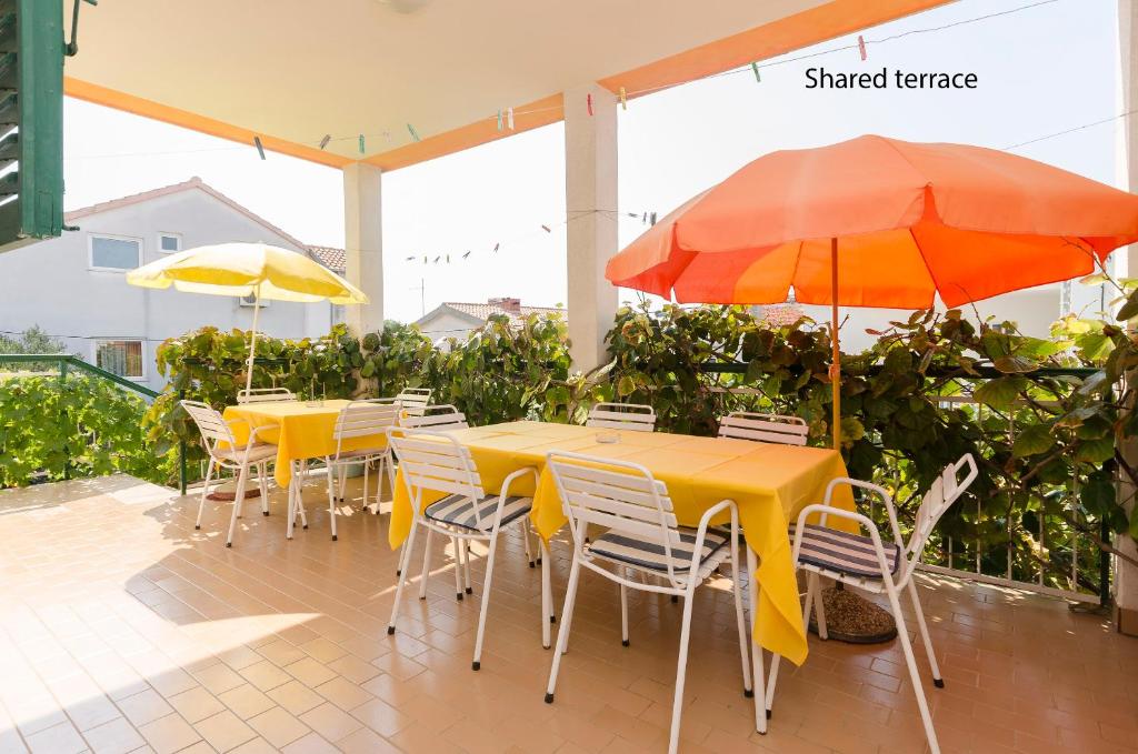 a row of tables and chairs with umbrellas on a patio at Rooms Dejana in Vodice