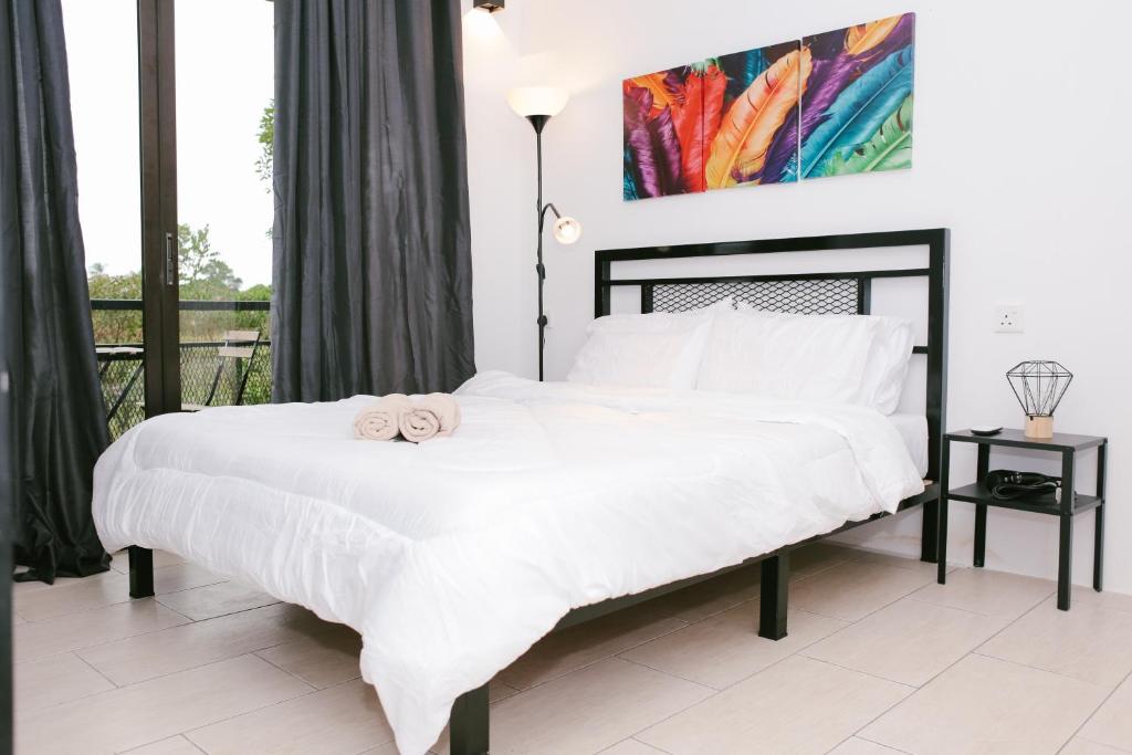 a bedroom with a large white bed with two towels on it at Langkawi Green View Cottage in Pantai Cenang