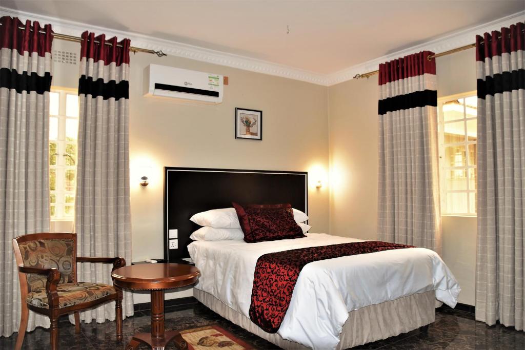 a bedroom with a bed and a table and a chair at Annavilla7 Lilongwe Aparthotel in Lilongwe