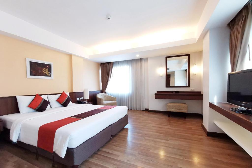 a hotel room with a large bed and a television at Avion Hotel in Lat Krabang