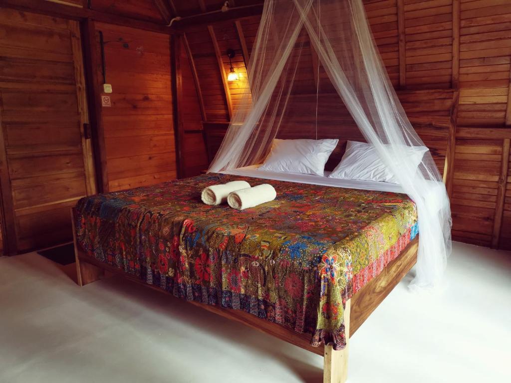 ein Schlafzimmer mit einem Bett mit zwei Handtüchern darauf in der Unterkunft Coconut Tree Cottages in Batukaras