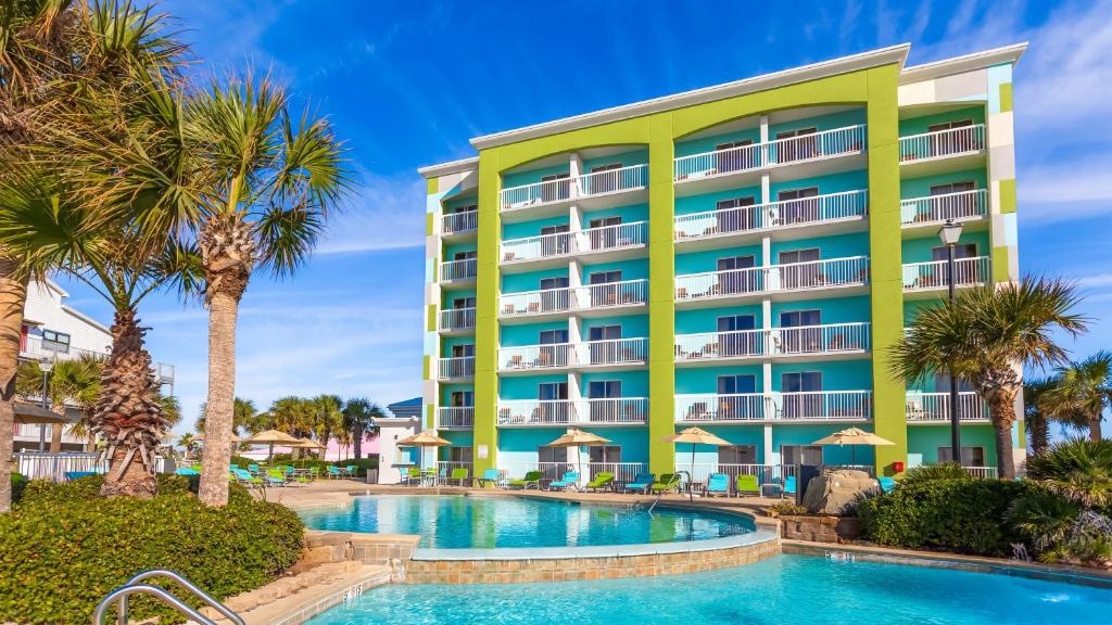a hotel with a swimming pool and palm trees at Holiday Inn Express Orange Beach - On The Beach, an IHG Hotel in Orange Beach