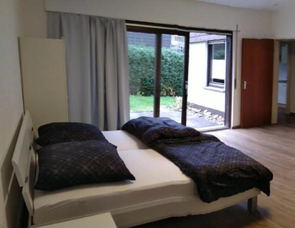 een bed met kussens in een kamer met een raam bij Kleine Ferienwohnung, Einzimmeraparment in Altenkirchen in Almersbach