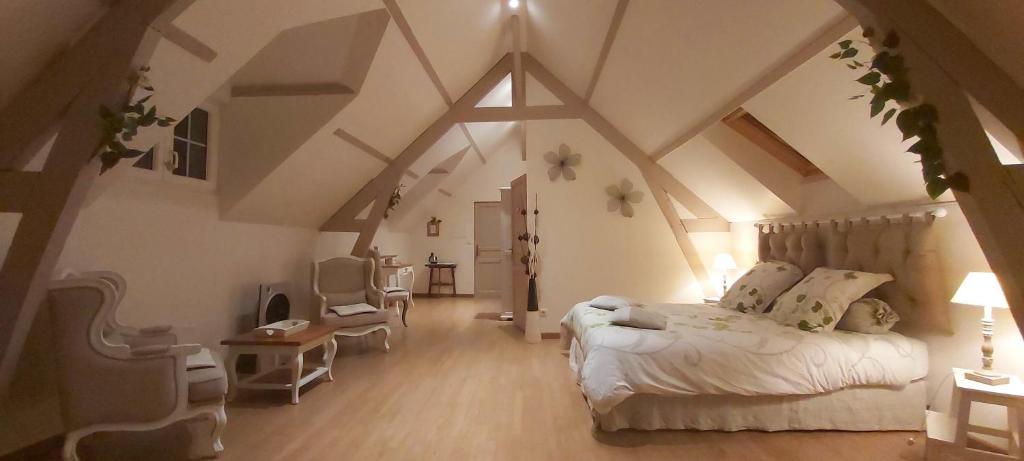 ein Dachzimmer mit einem Bett und einem Stuhl darin in der Unterkunft Un Parfum de Campagne in Méaulte