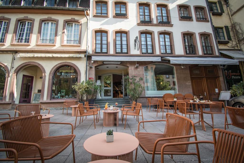 un patio avec des tables et des chaises en face d'un bâtiment dans l'établissement Hotel Rohan, Centre Cathédrale, à Strasbourg