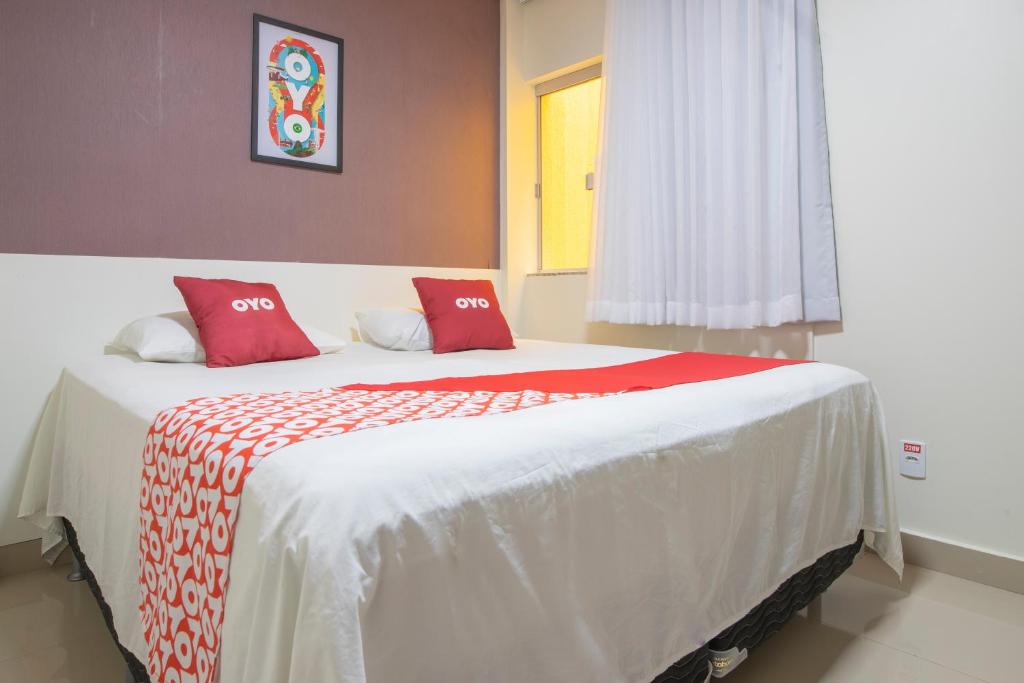 a bedroom with a large bed with red pillows at OYO Tropical Confort Hotel, Brasilia in Brasilia