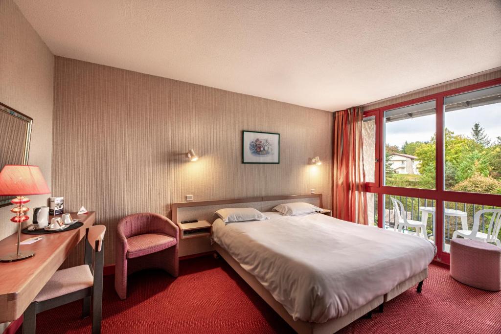 Lacapelle-ViescampにあるHôtel du Lacのベッド、デスク、窓が備わるホテルルームです。