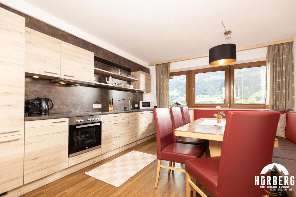 a kitchen with a wooden table and red chairs at HORBERG Appartements in Schwendau