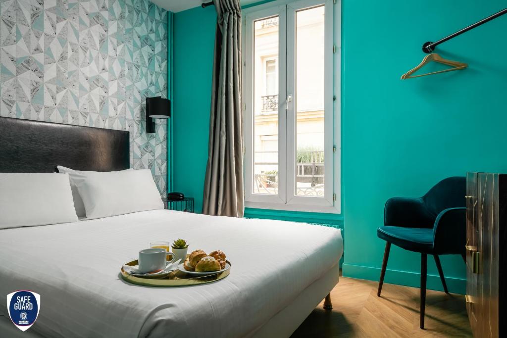 Una habitación de hotel con una cama con una bandeja de comida. en Hotel Elysée Etoile, en París