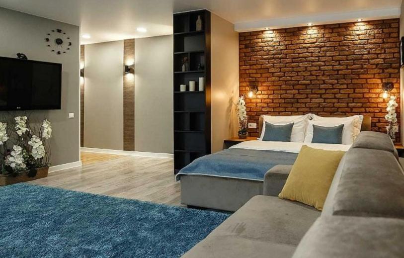 a bedroom with a large bed and a brick wall at Apartament on Sovetskaya 80 in Bobruisk