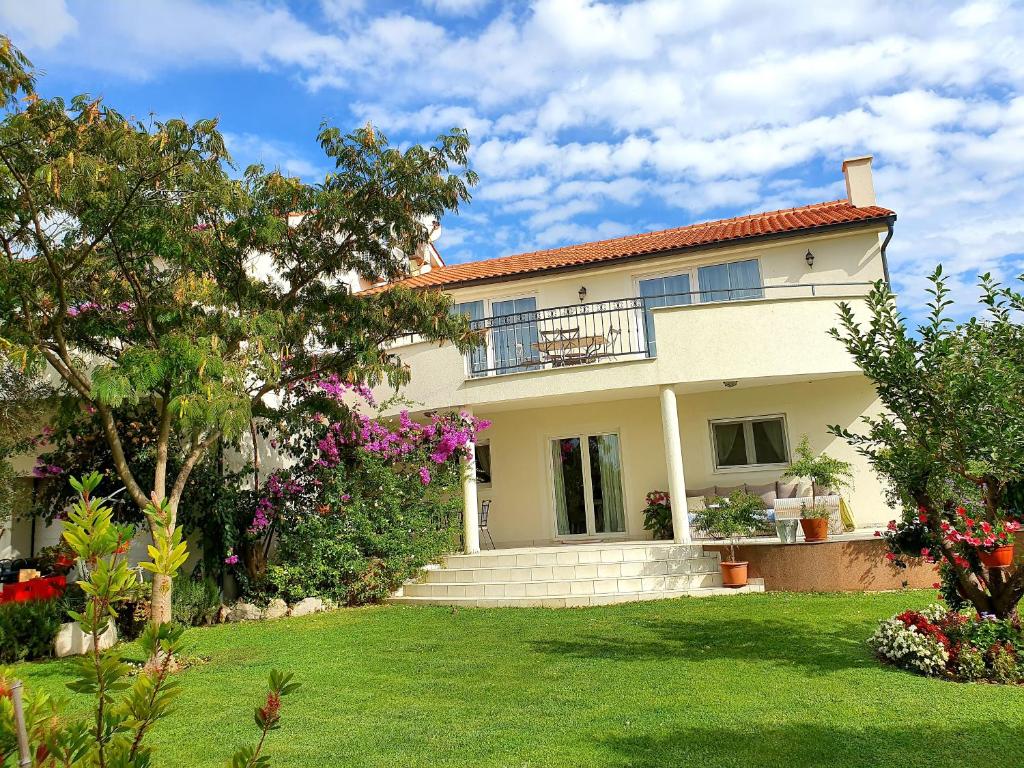 una casa blanca con un patio con flores en Apartment Oaza Mira, en Tribunj