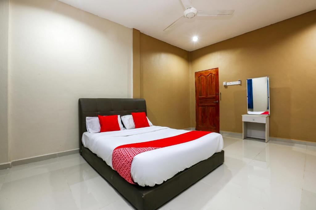a bedroom with a large bed with red and white sheets at OYO 89933 Nun Hotel in Jeli