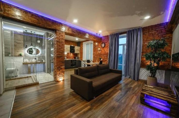 a living room with a brown couch and a brick wall at Apartament on Gorkogo 23 in Bobruisk