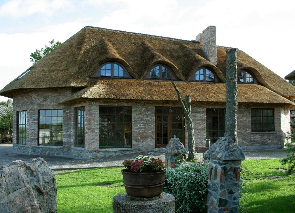 a large stone house with a thatched roof at Meškių dvarkiemis in Bubiai