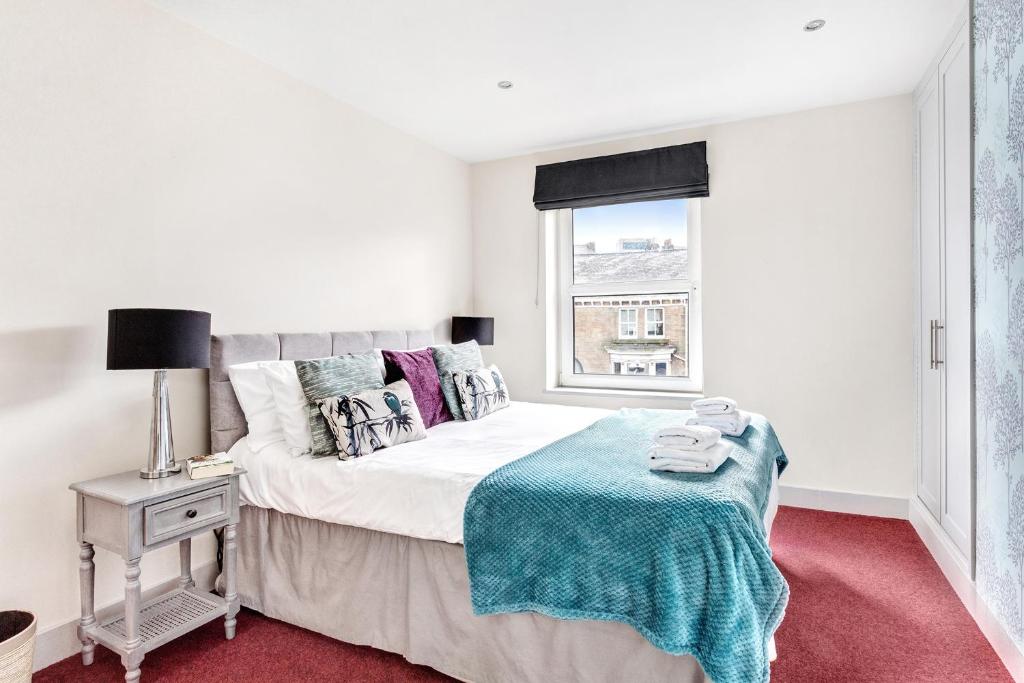 een witte slaapkamer met een bed en een raam bij Granville Apartments Harrogate in Harrogate