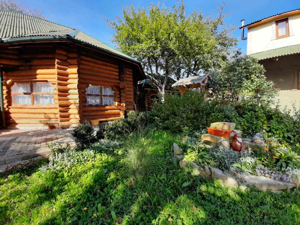 um chalé de madeira com um jardim em frente em Прутець em Mykulychyn