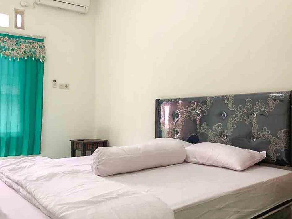 un letto con due cuscini sopra di Griya Fadamas Syariah near Taman Hijau Demangan Madiun Mitra RedDoorz a Madiun