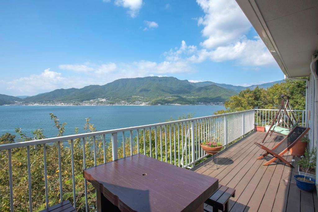 uma varanda com uma mesa e vista para um lago em Sen Guesthouse em Shodoshima