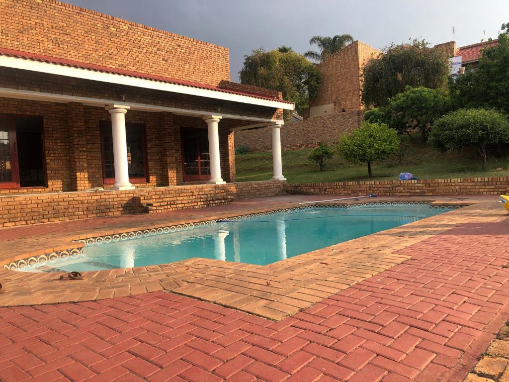 a swimming pool in front of a brick building at Sunrise Boutique Hotel in eMalahleni