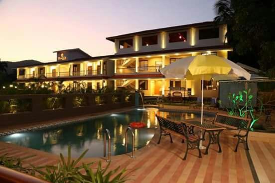 a house with a pool and a table and an umbrella at Meritas Seawind Beach Resort, Shrivardhan in Srīvardhan