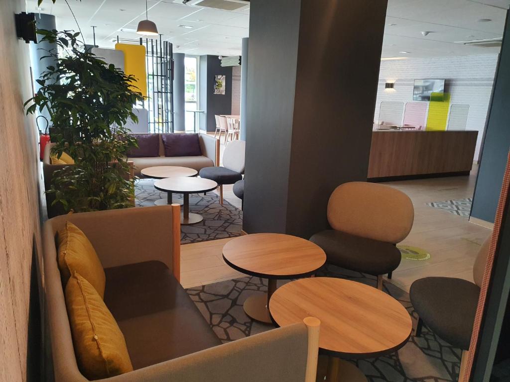 a waiting area with tables and chairs in a lobby at B&B HOTEL Ouistreham in Ouistreham