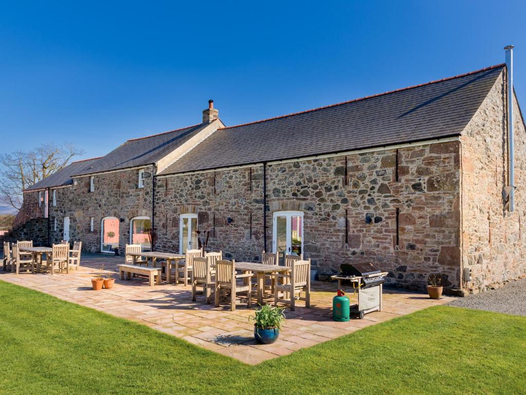 a stone building with tables and chairs in front of it at The Outbuildings in Gaerwen