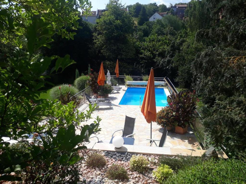 einen Pool mit Sonnenschirmen und Stühlen sowie einen Pool in der Unterkunft Ferienwohnung Pension am Weinberg in Mainstockheim