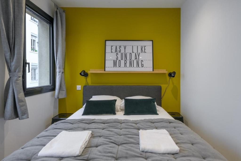 a bedroom with a large bed with a yellow wall at NOCNOC - Le Michelangelo in Lyon
