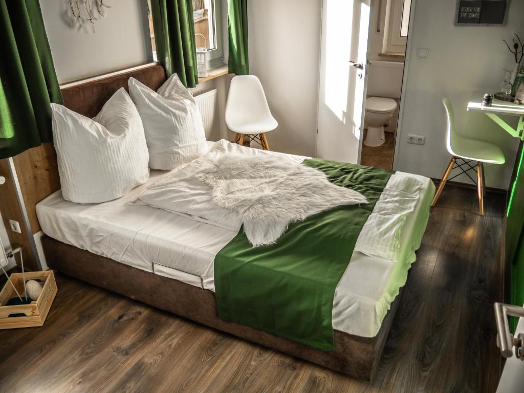 Schlafzimmer mit einem Bett mit grüner Bettwäsche und weißen Kissen in der Unterkunft Waldhotel Zollhaus in Nürnberg