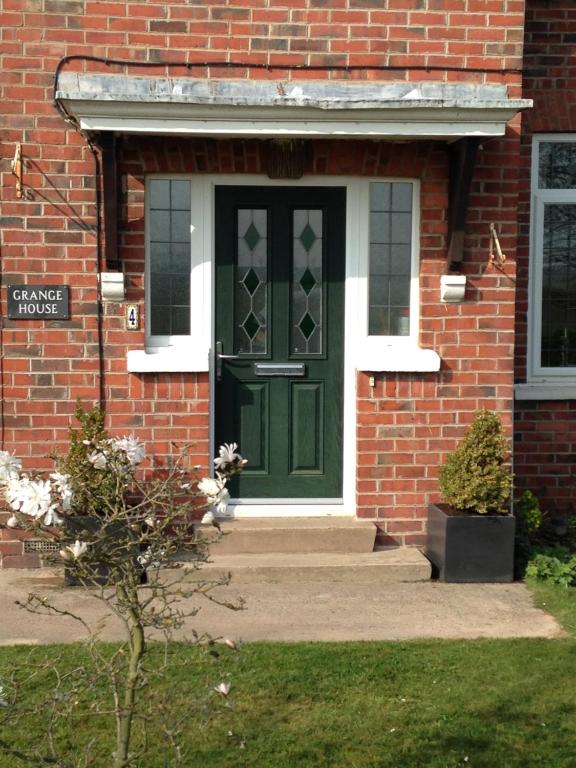 a green front door of a brick building at Grange House Bed & Breakfast in Lowdham