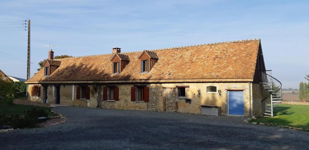 een oud stenen huis met rode deuren en een oprit bij Le hameau in Duneau