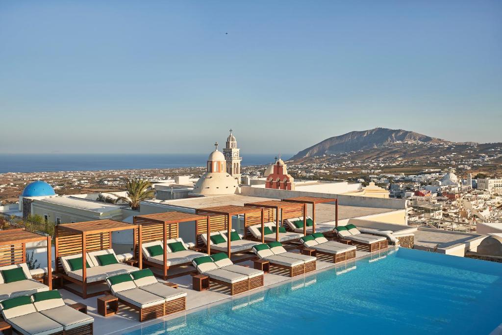 - une piscine avec des chaises longues et une vue sur la ville dans l'établissement Katikies Garden Santorini - The Leading Hotels Of The World, à Fira