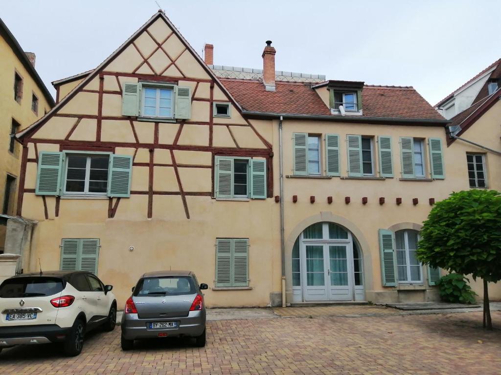 une maison avec deux voitures garées devant elle dans l'établissement La Cour de Berthe Ouest, à Colmar