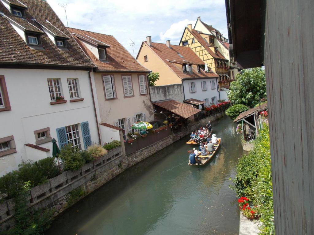 a group of people riding in boats down a river at Petite Venise in Colmar