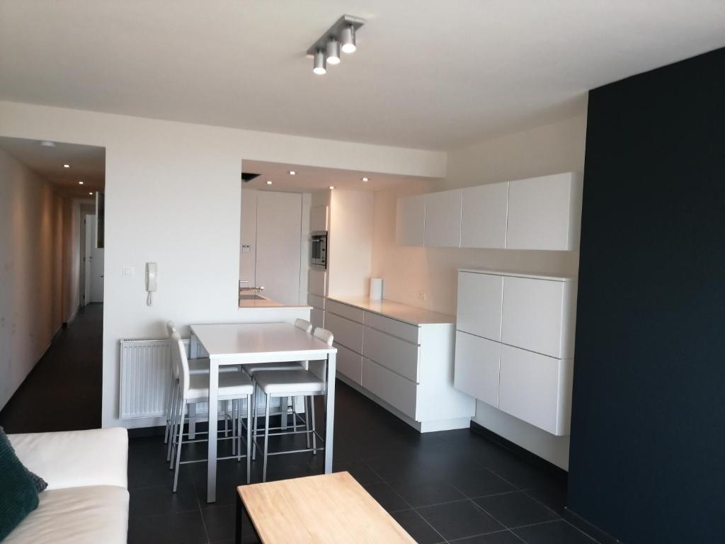 a kitchen with white cabinets and a table and chairs at Marjolaine Zeezicht - Nieuwpoort-bad met GRATIS garagebox in Nieuwpoort