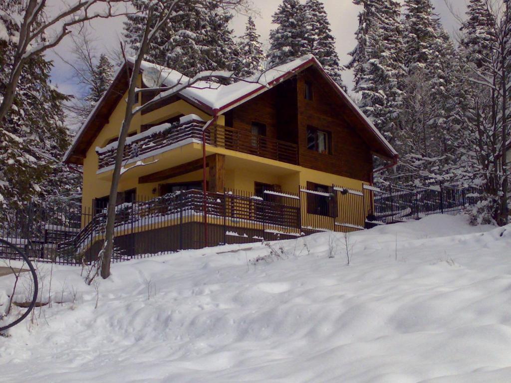 una baita di tronchi nella neve con neve di Vila Piscul Ursului a Predeal